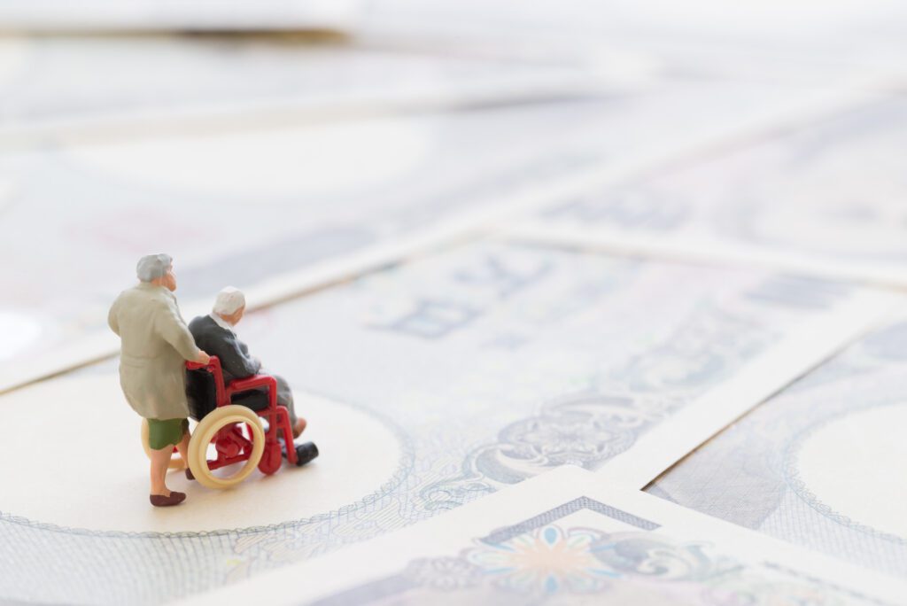 Elderly couple mini-figures placed on bank notes. Metaphor of navigating the cost of care reform.